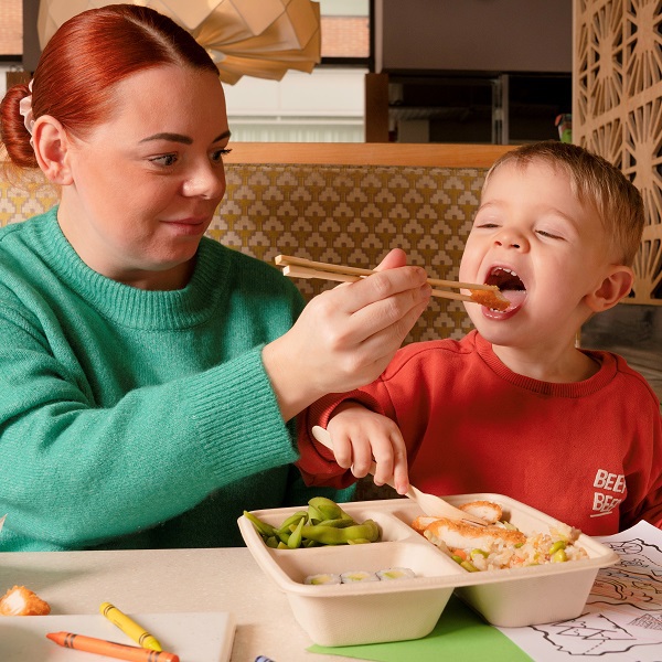 Mum feeding her son with chopsticks